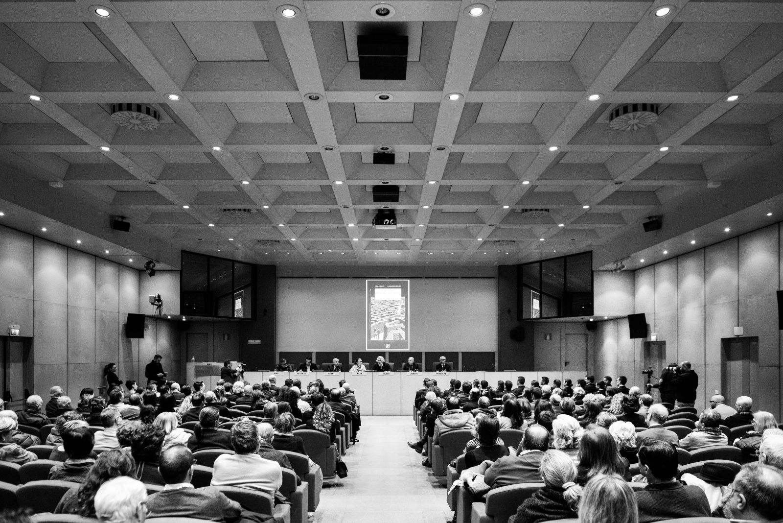 Sala congressi gremita ripresa dal fondo, fotografia in bianco e nero
