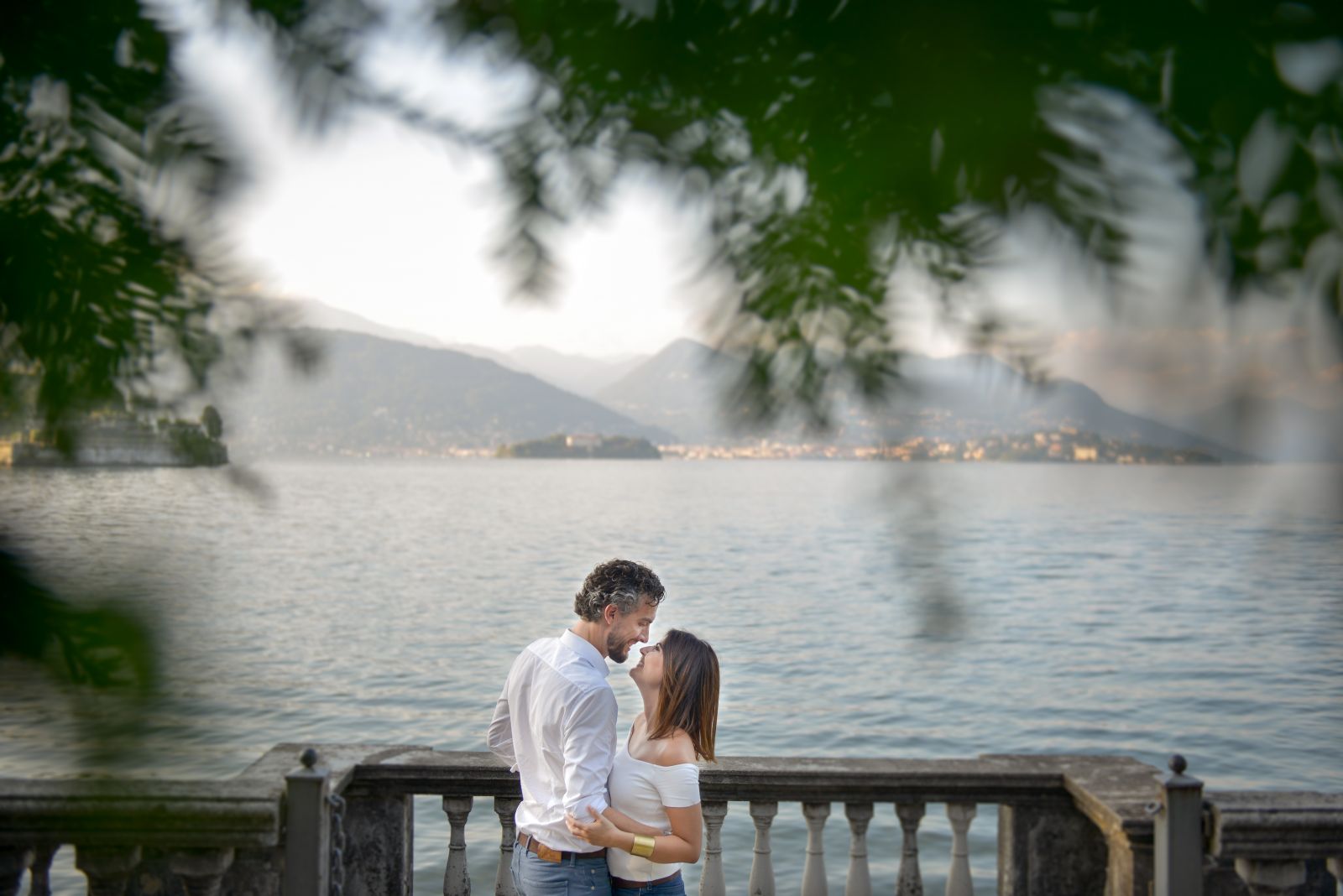 Coppia che si bacia su una balconata affacciata sul lago al tramonto