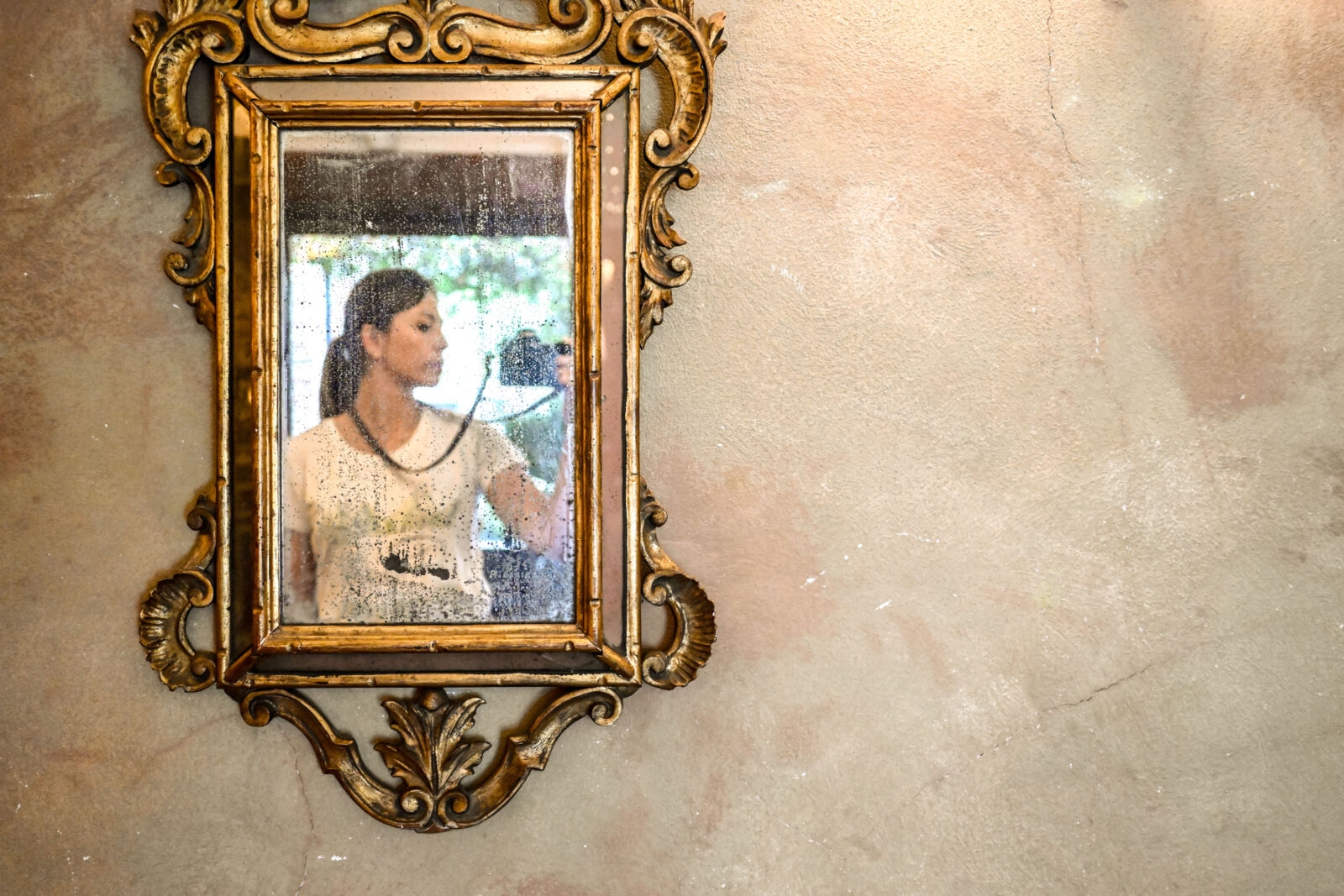 La sposa riflessa in un antico specchio con cornice dorata appeso a una parete affrescata