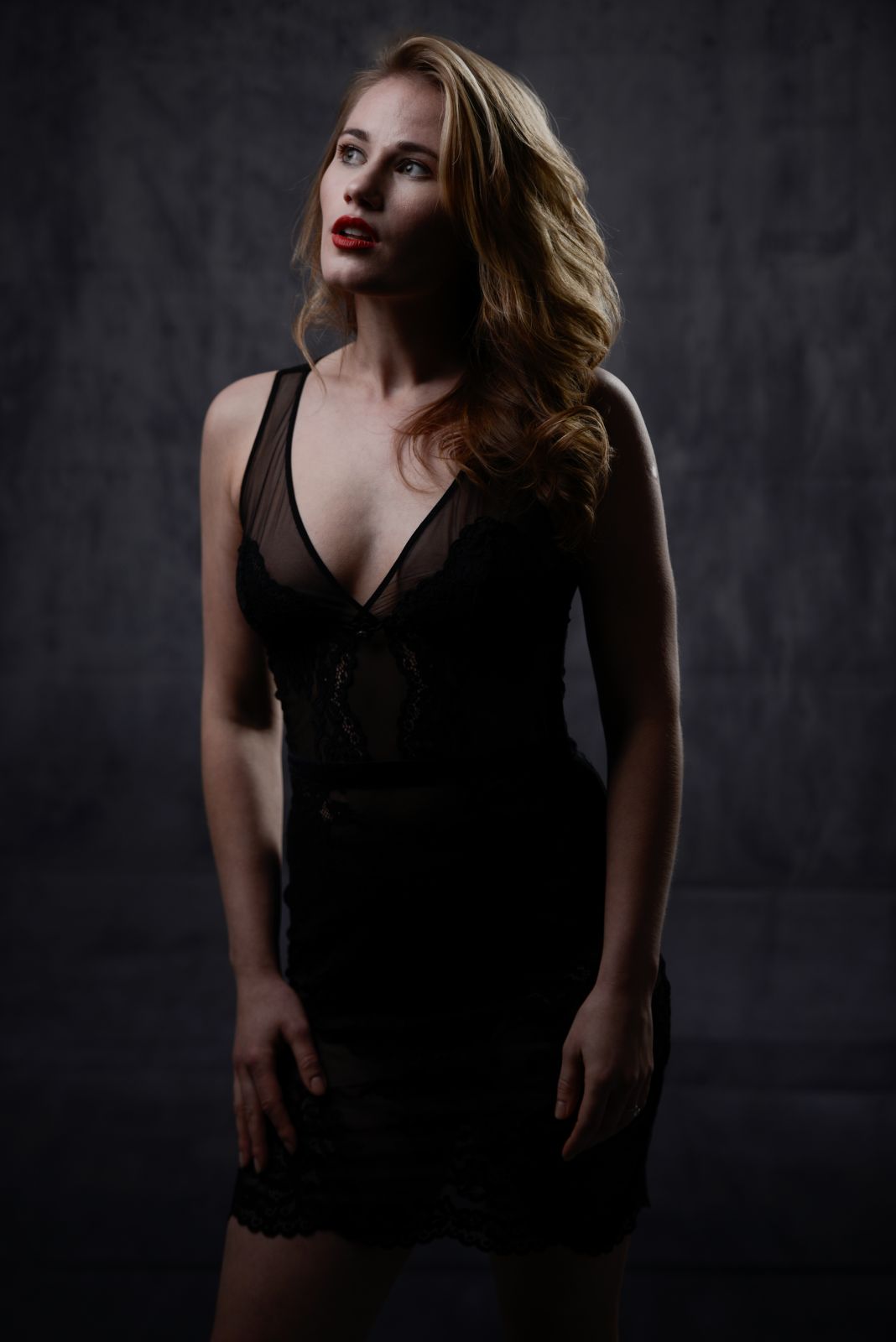 Ritratto in studio di una donna in abito nero, luce laterale su fondo scuro