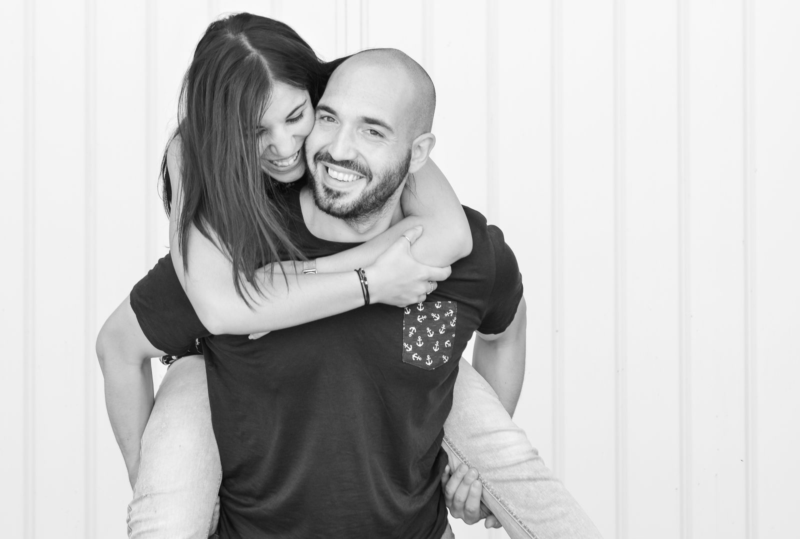 Coppia che gioca a cavalluccio davanti a una parete bianca, fotografia in bianco e nero