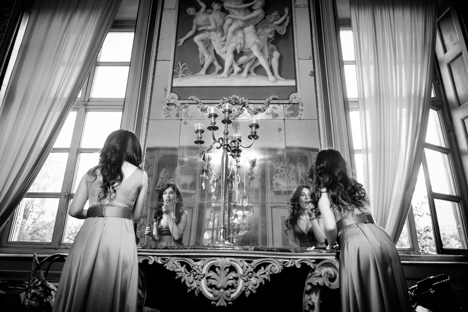 I preparativi riflessi in un grande specchio antico accanto alla finestra, fotografia in bianco e nero