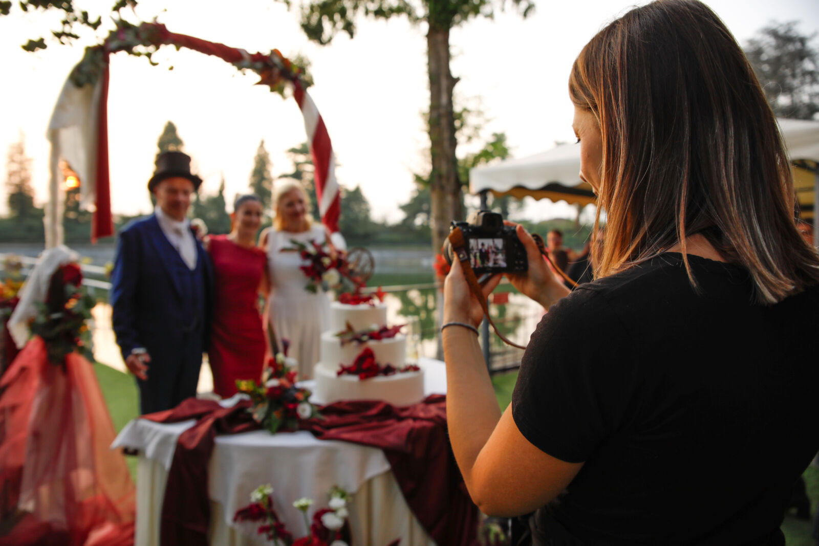 La fotografa al lavoro durante una cerimonia all'aperto sotto un arco di fiori