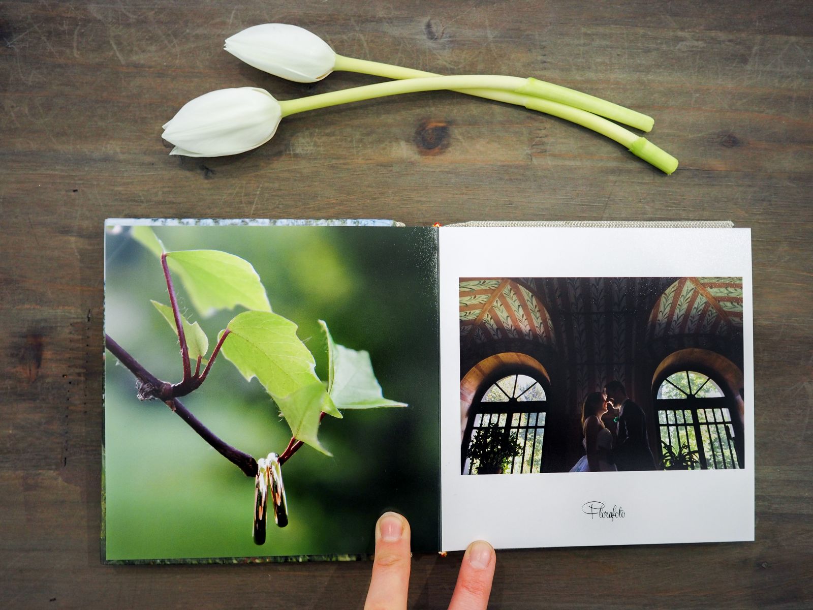 Mani che sfogliano un fotolibro matrimoniale aperto su una doppia pagina